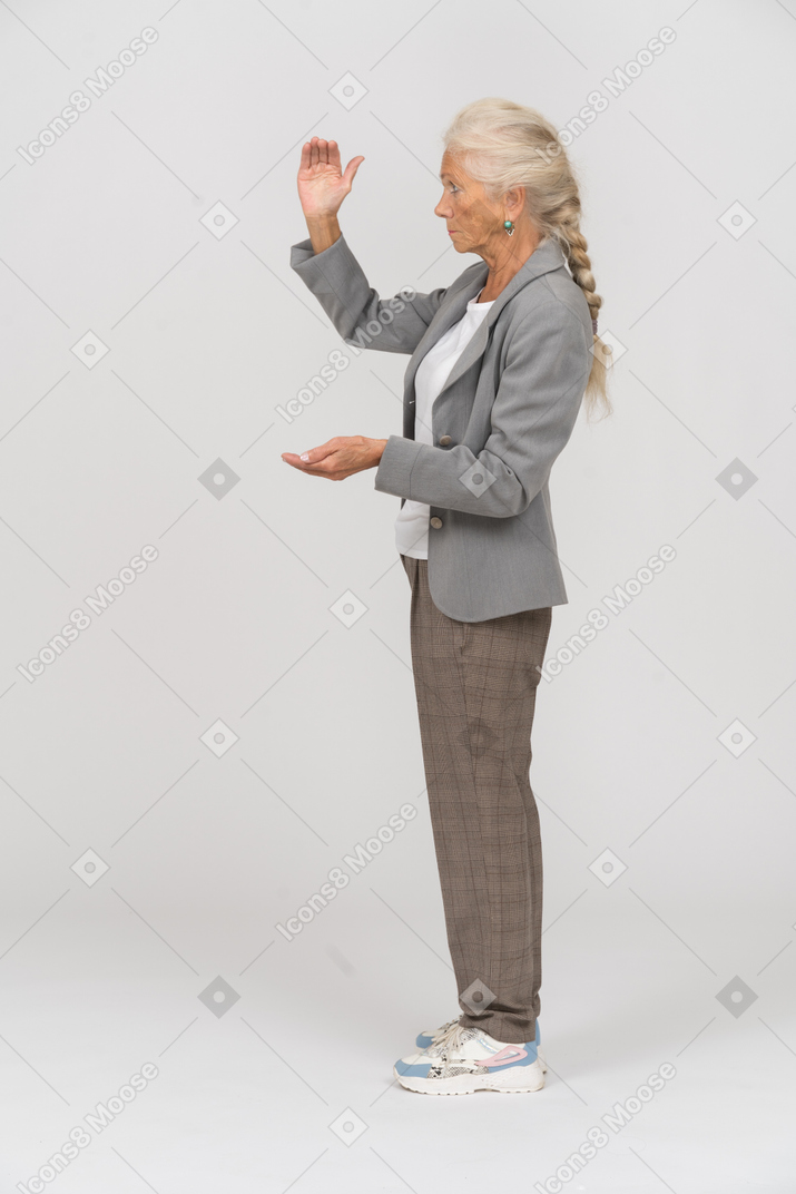 Vista lateral de una anciana en traje que muestra el tamaño de algo