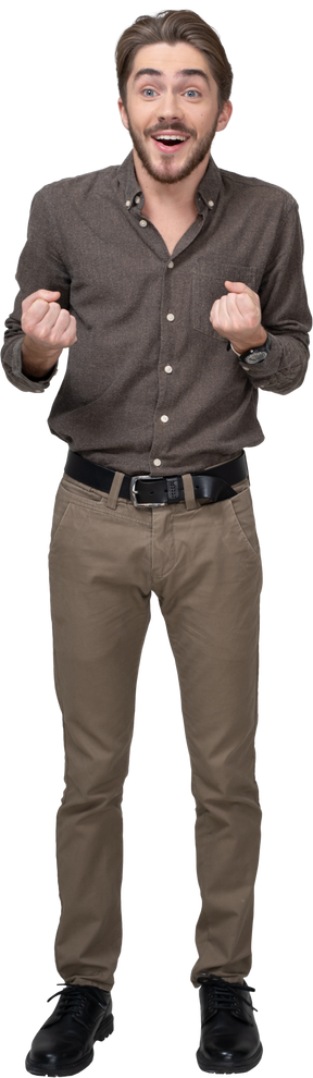 Front view of a delighted young man in office clothing clenching fists
