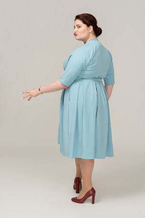 Vista posteriore di una donna in abito blu che fa smorfie
