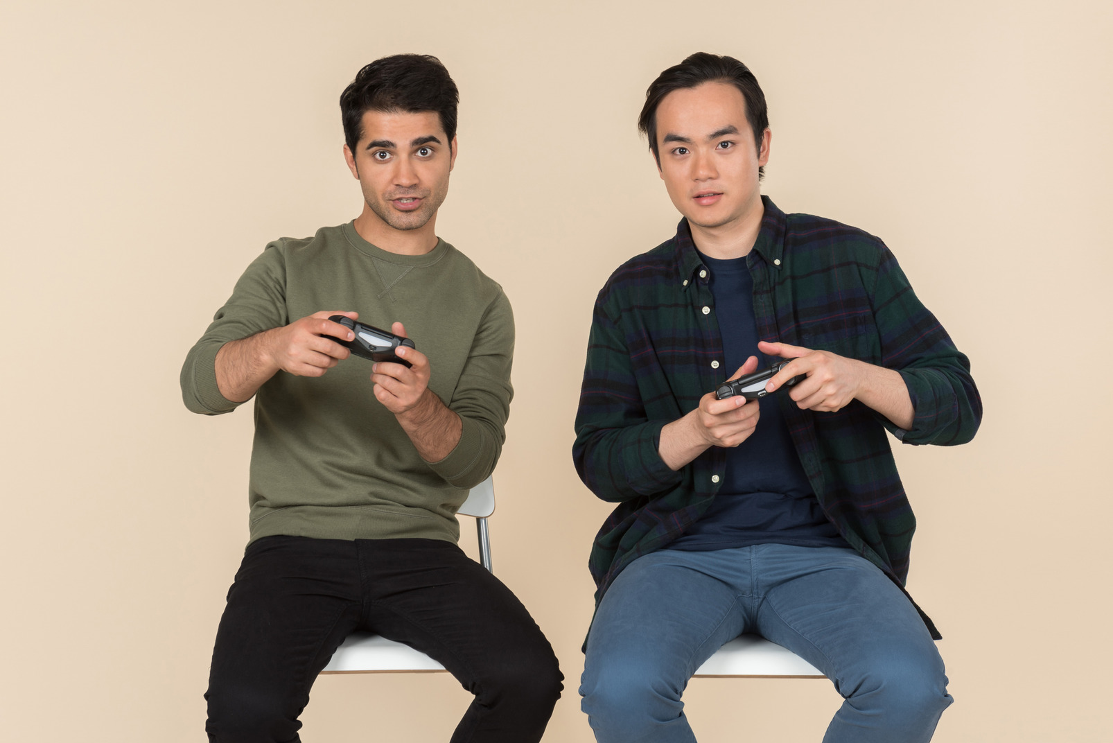 Interracial friends sitting in chairs and playing video games
