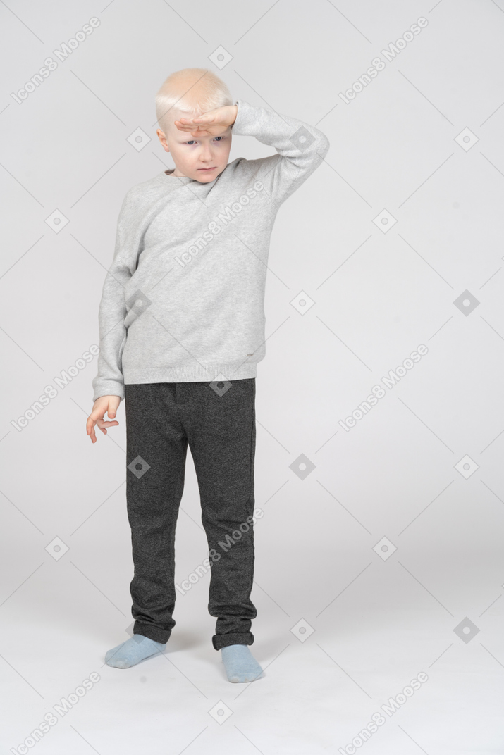 Boy looking at something with hand at his forehead