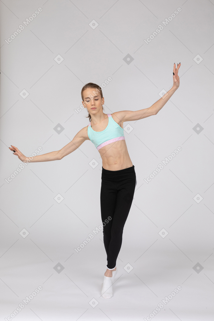 Vorderansicht eines jugendlich mädchens in der sportbekleidung, die auf ihren zehenspitzen balanciert