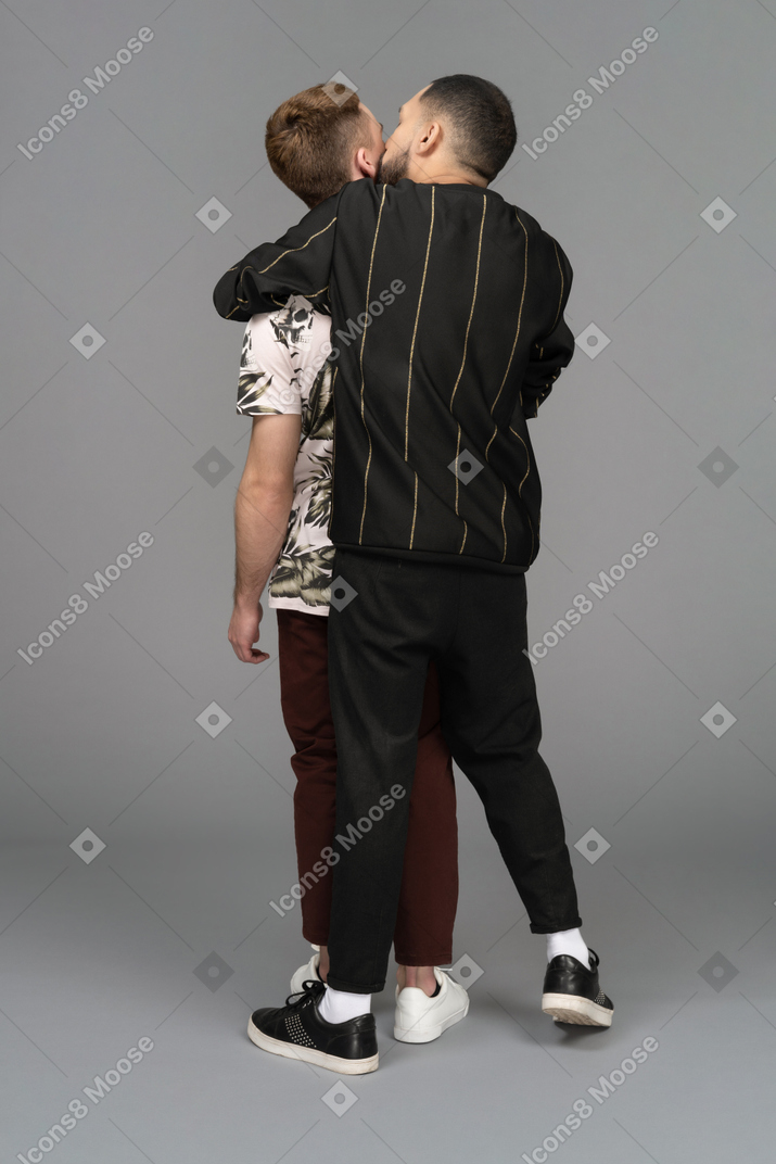 Vista traseira de um jovem abraçando outro apaixonadamente pelas costas