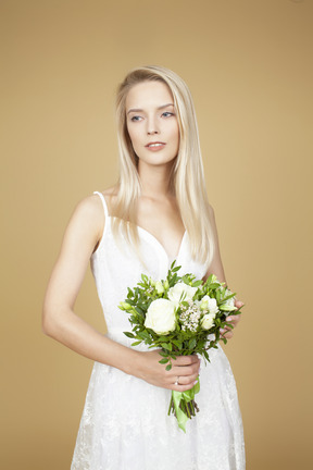 Schöne braut, die einen hochzeitsblumenstrauß von weißen blumen hält