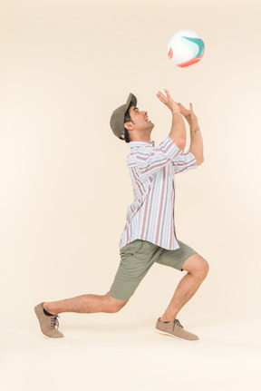 Young caucasian guy standing in profile and holding ball