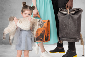 A girl holding a cat next to a man's and a woman's bag
