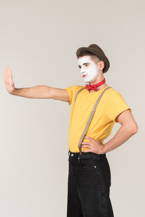 Male clown elongating hand and showing stop sign