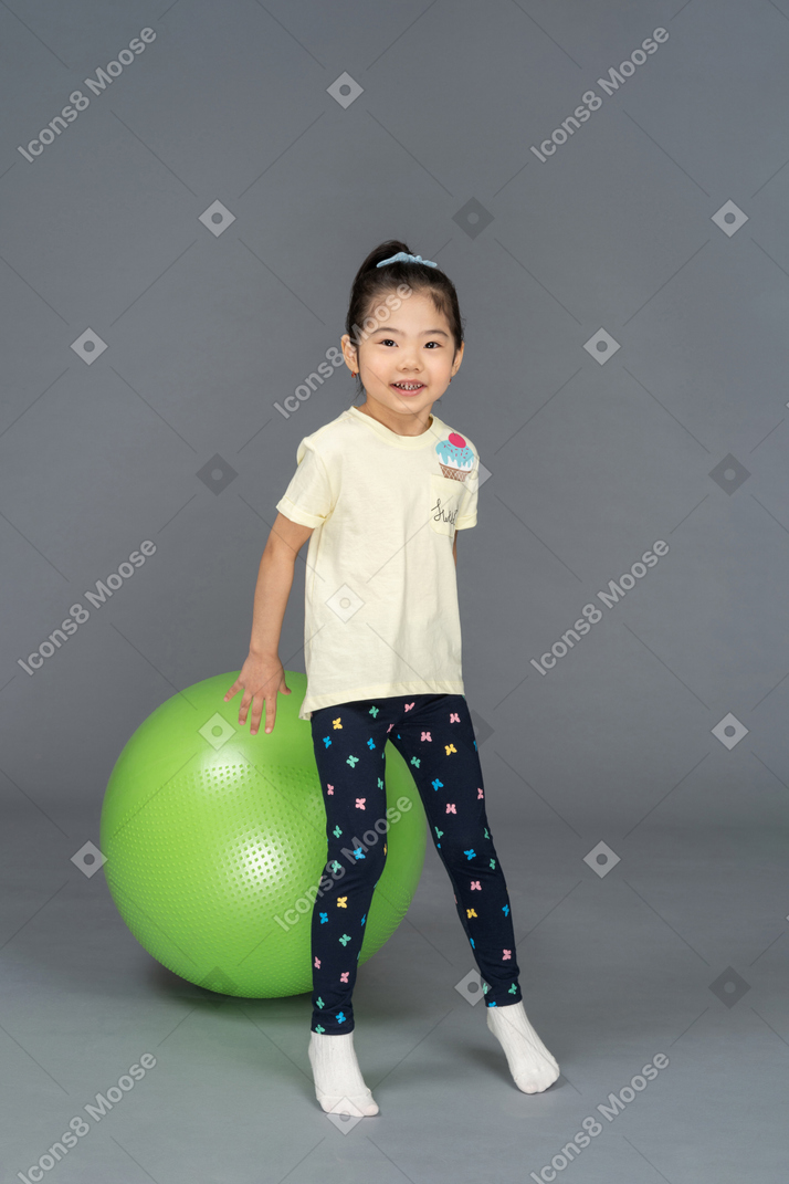 녹색 fitball 앞에 서 있는 어린 소녀