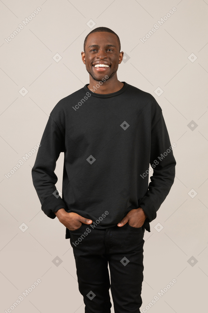Young man with wide smile keeping hands in pockets