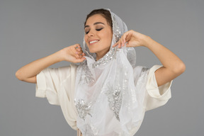 Close up of a smiling arab woman adjusting her beautiful white headscarf