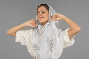 Gros plan d'une femme arabe souriante ajustant son beau foulard blanc