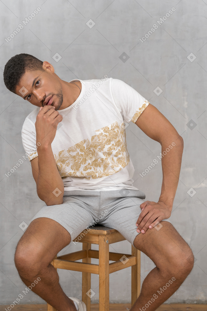 Young man sitting and touching chin