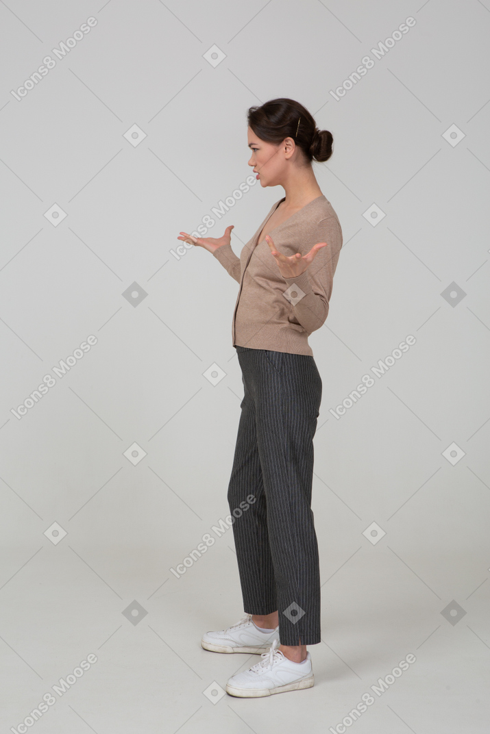 Side view of a perplexed gesticulating young lady in beige pullover