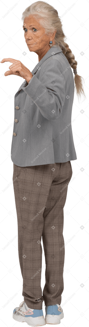 Vista trasera de una anciana en traje mostrando un tamaño pequeño de algo