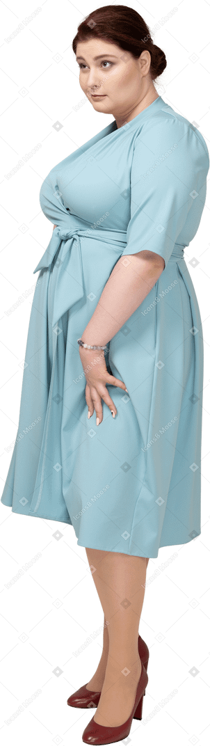 Woman in blue dress standing in profile