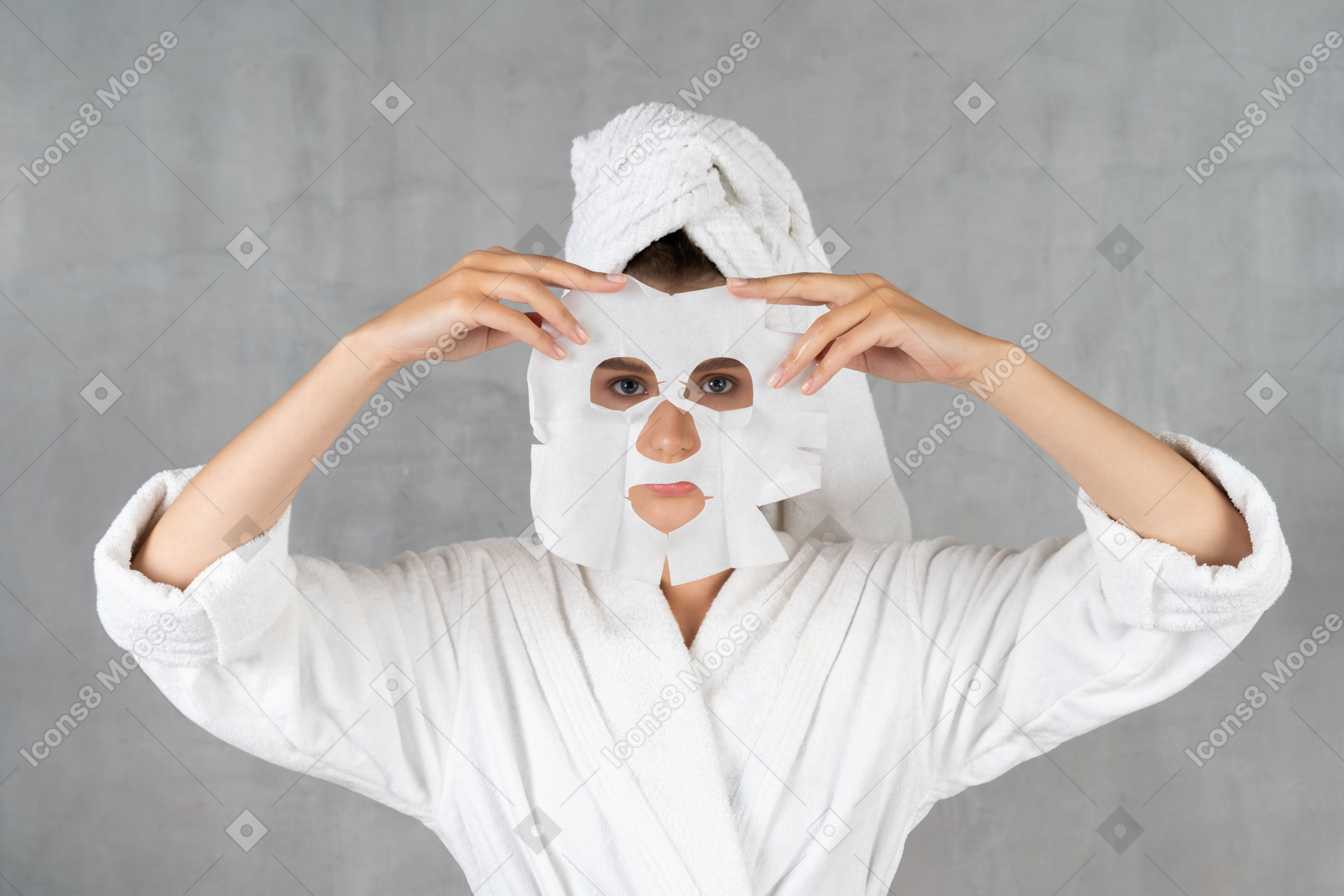 Woman in bathrobe holding a sheet mask over face