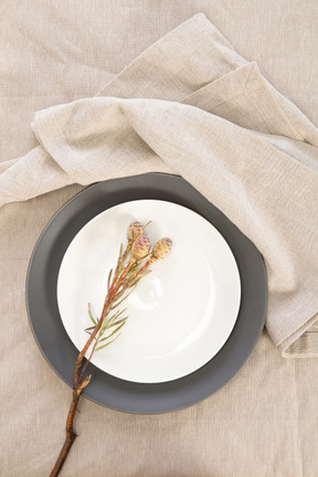 Black and white plates and twig on tablecloth