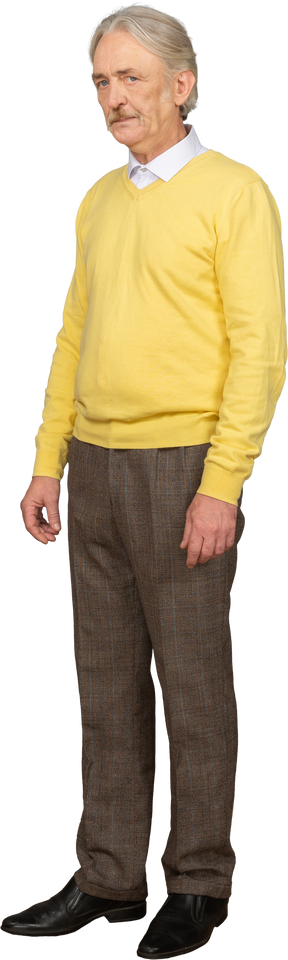 Вид в три четверти недовольного старика в желтом пуловере, смотрящего в камеру