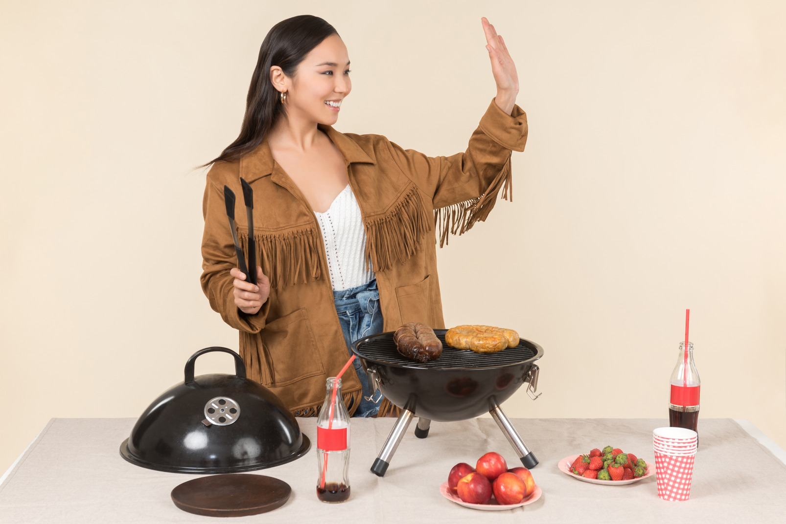 Young asian woman preparing bbq and waving with a hand