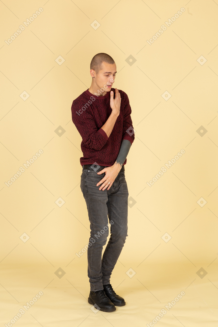 Вид в три четверти молодого грустного человека в красном пуловере, смотрящего в сторону