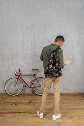 Three-quarter back view of a man examining a map