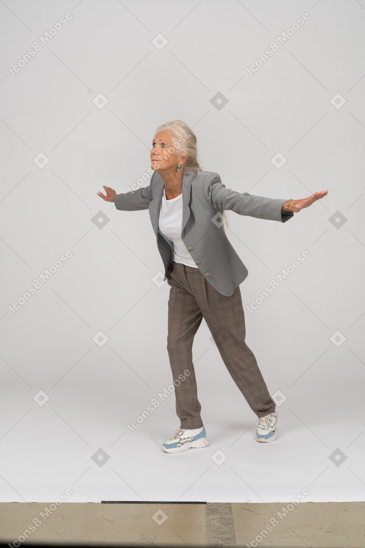 Side view of an old lady in suit standing with outspreading arms