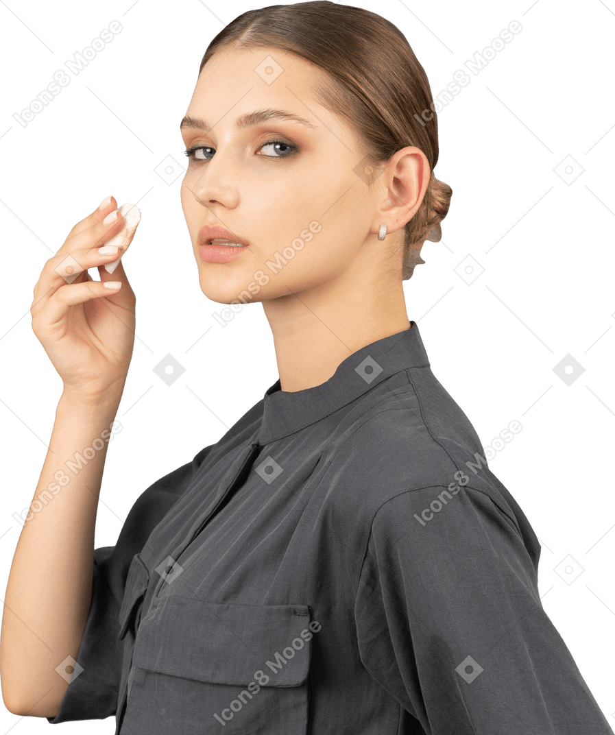 Side view of a young woman in a jumpsuit removing eye make-up
