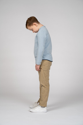 Vista lateral de un niño inclinando la cabeza hacia abajo