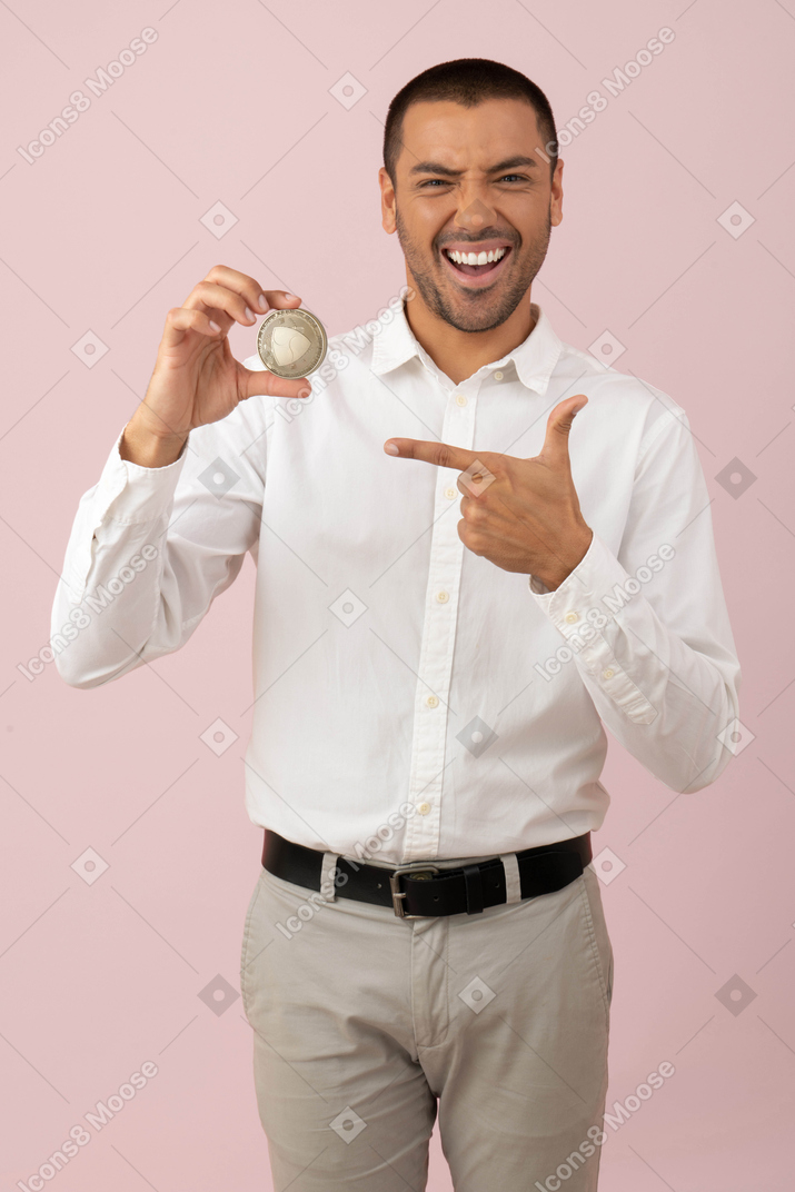 Attraktiver junger mann hält eine nem münze