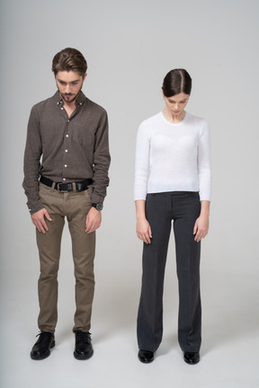Front view of a young couple in office clothing looking down
