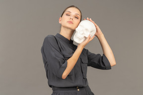 Front view of a young woman in a jumpsuit holding a plaster skull