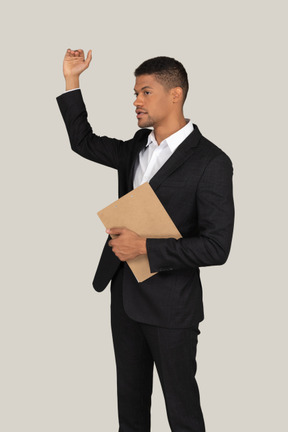 Young office worker in suit holding folder and showing height of something