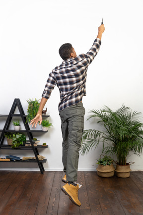 Three-quarter back view of a tourist reaching up with a knife