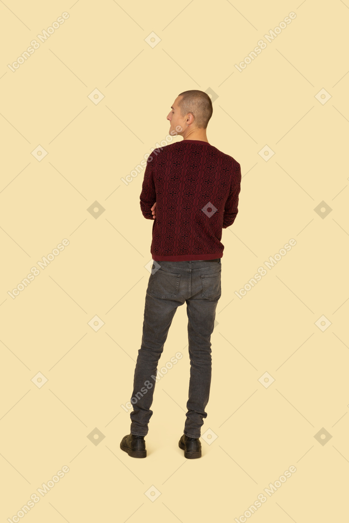 Back view of an offended young man dressed in casual clothes crossing his hands