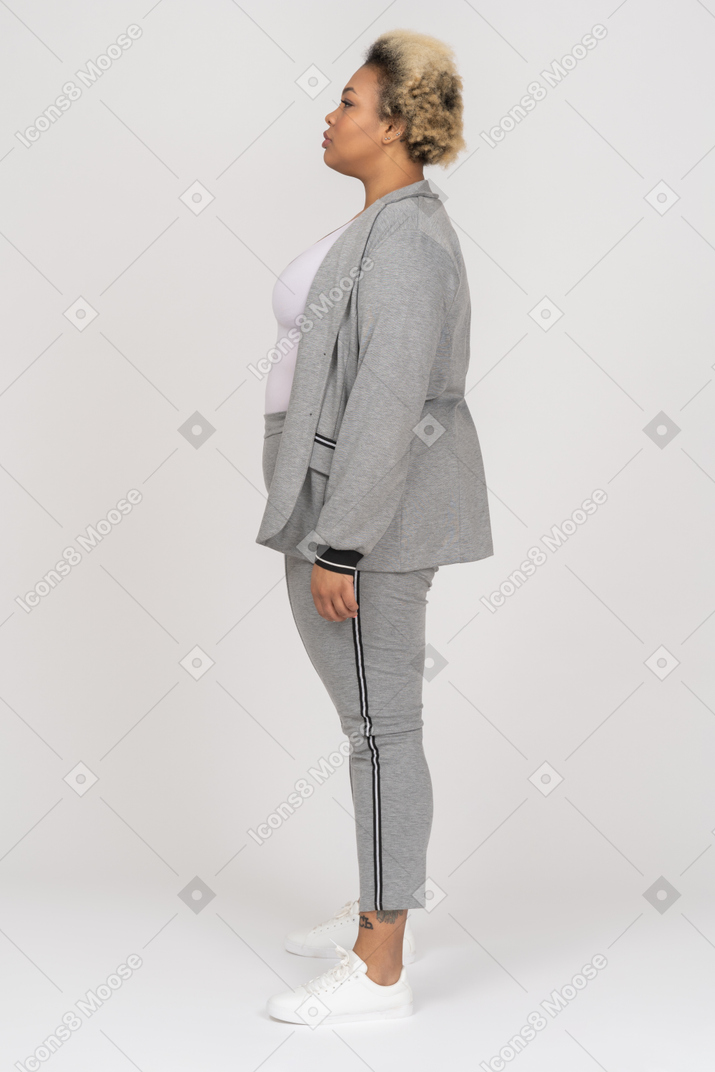 Mulher de pele escura em um terno esporte cinza posando de perfil