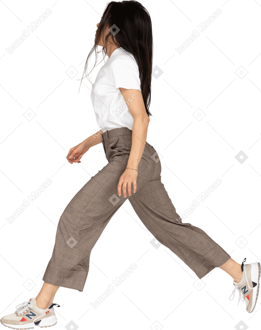 Vista lateral de una señorita saltando en calzones y camiseta extendiendo las piernas