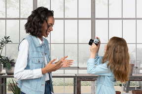 Little girl taking picture of a woman on camera