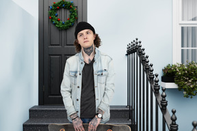 A young man holding a skateboard in front of a door