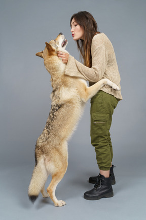 De cuerpo entero de una maestra feliz besando a su perro