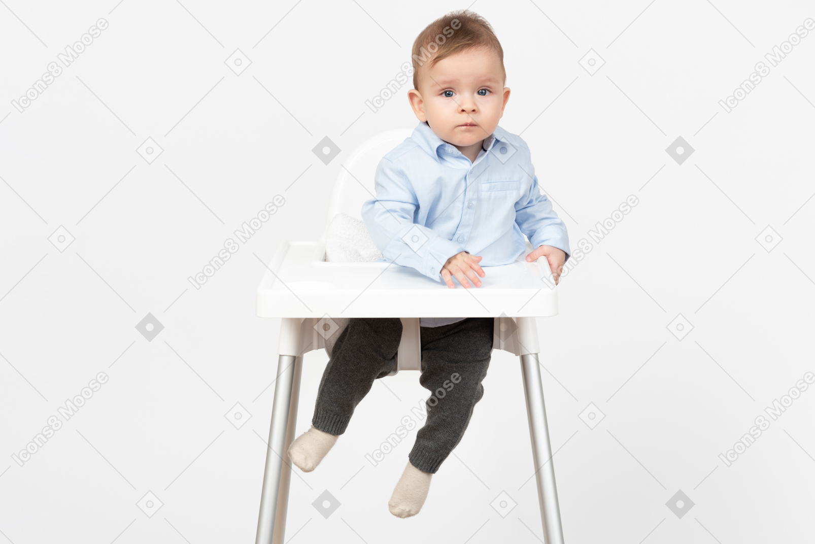 Прелестный маленький мальчик сидит в стульчике