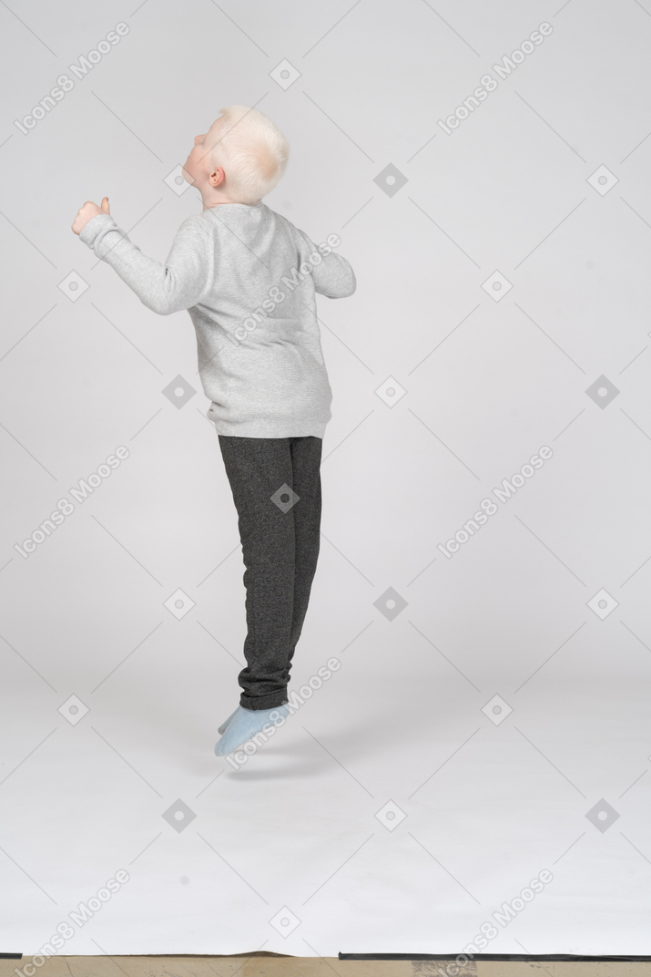 Вид сзади на прыгающего мальчика в три четверти