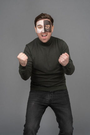 Front view of a screaming male football fan clenching fists