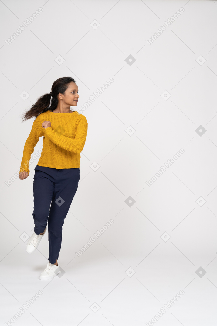 Vista frontal de uma garota com roupas casuais correndo para a frente
