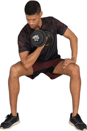 Young man in sports clothes lifting weigths