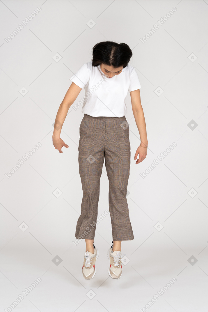 马裤和t恤的跳跃的年轻女士的前视图