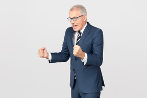 Angry mature businessman holding clenched fists up