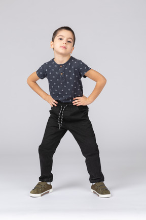 Vue de face d'un garçon mignon posant avec les mains sur les hanches
