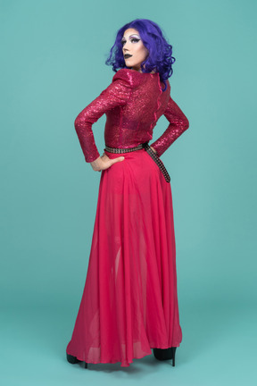 Rückansicht einer drag queen in rosafarbenem kleid, die mit den händen auf den hüften posiert