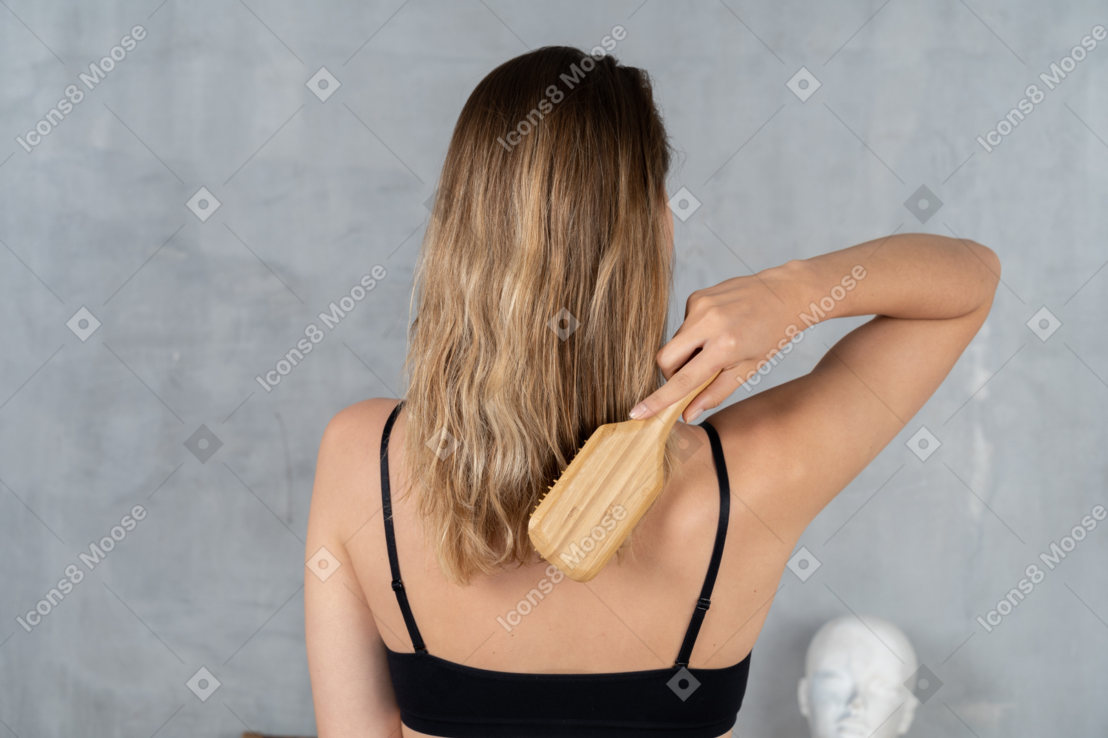 Vista posteriore di una giovane donna che si spazzola i capelli