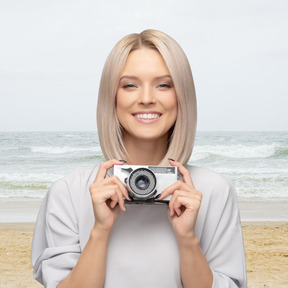 A woman holding a vintage camera on the beach